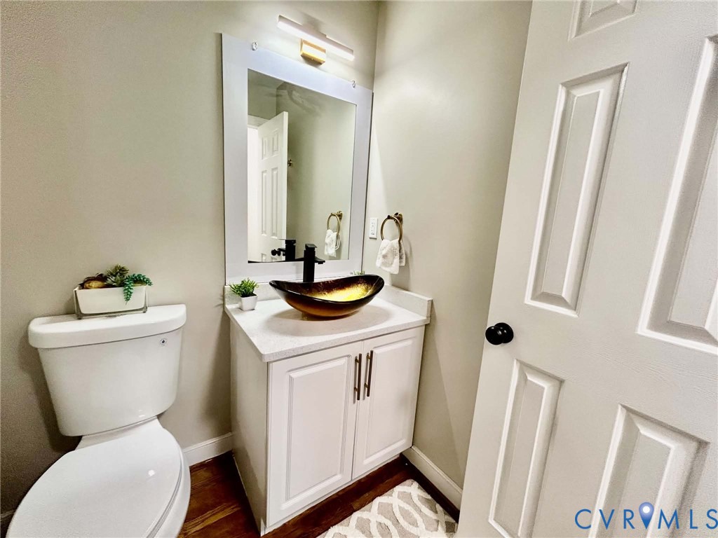 Vanity featuring a stone-composite countertop, vessel sink, matte black faucet, and white shaker-style cabinetry with metal pulls