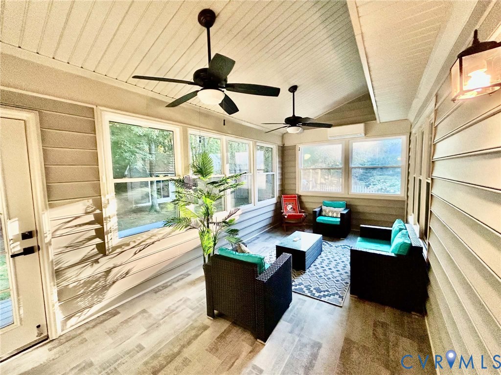 Enclosed porch featuring wood-finish flooring, vaulted ceilings with dual ceiling fans, horizontal siding, and multiple large windows