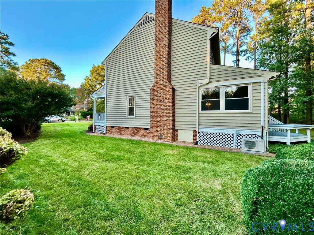 Exterior siding with a prominent full-height brick chimney, lattice foundation screening, and a side wooden deck