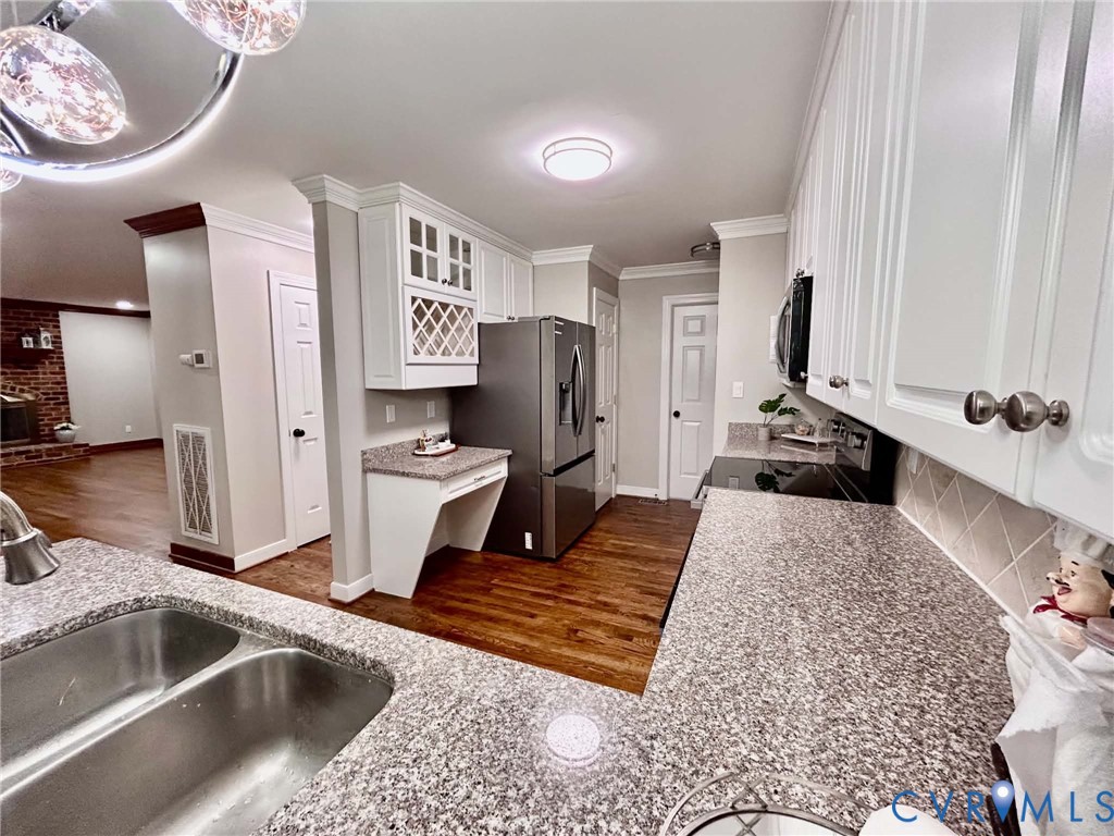 Kitchen featuring white cabinetry, stone-finish countertops, wood-finish flooring, built-in wine storage, and a dual-basin stainless steel sink