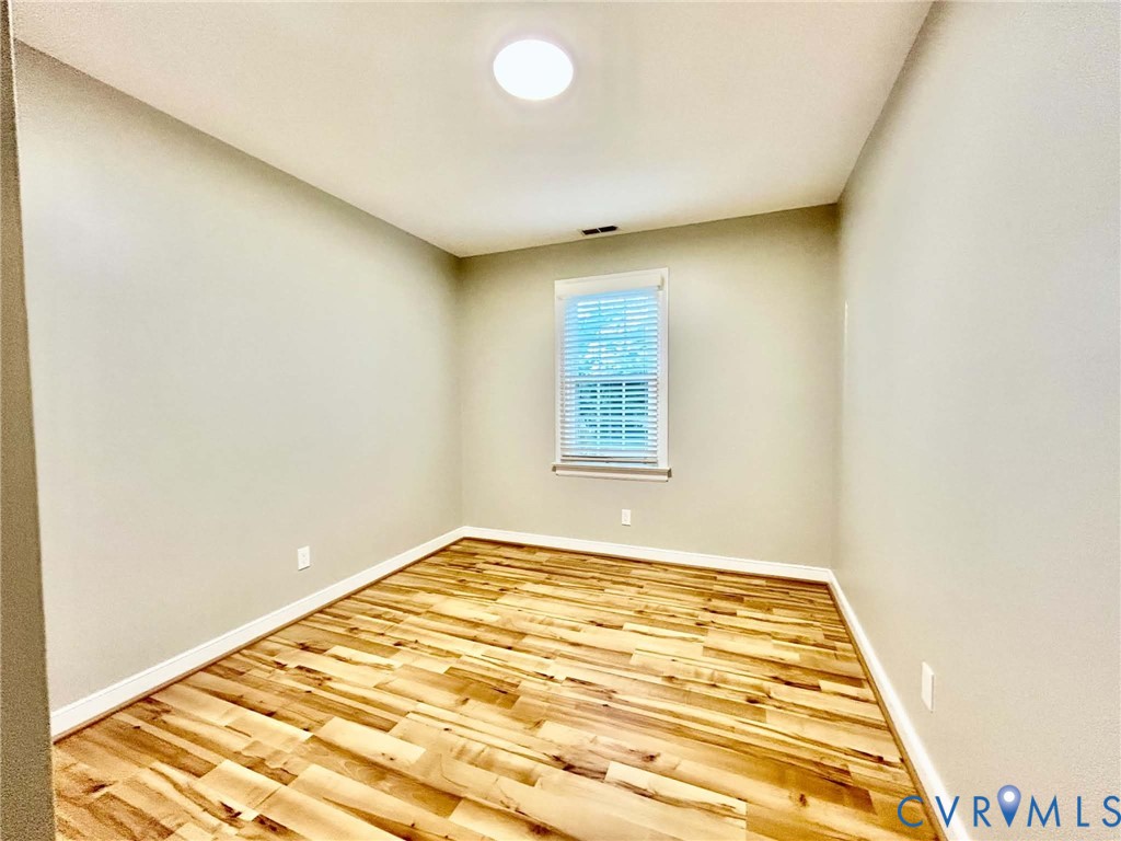 Room featuring wood-finish flooring, neutral wall paint, and a single window with installed blinds