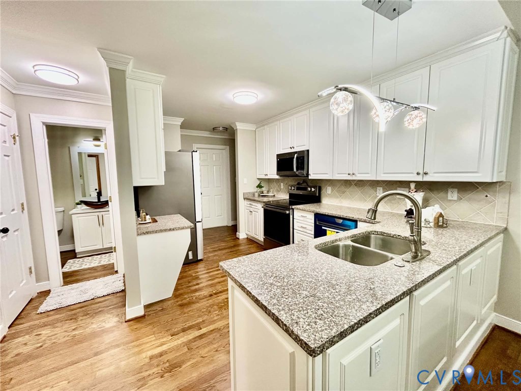 Kitchen featuring white cabinetry, stone-finish countertops, stainless steel appliances, a multi-globe pendant light fixture, and wood-finish flooring