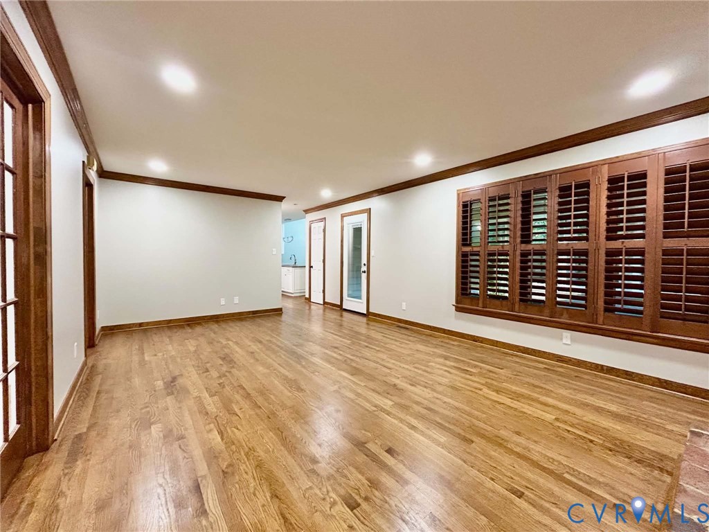 Interior featuring wood-finish flooring, recessed lighting, crown molding, plantation shutters, and multi-pane doors