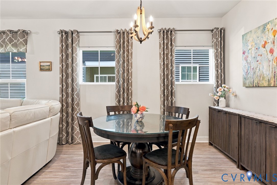 Wood-finish flooring, dual windows with grid inserts, and a tiered chandelier with wood-tone accents