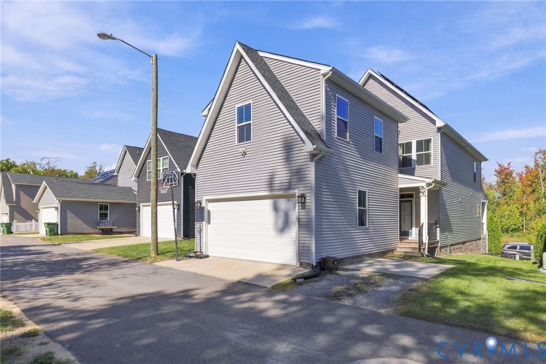 Two-story residence featuring grey vinyl siding, an attached two-car garage, and an asphalt-shingle roofline