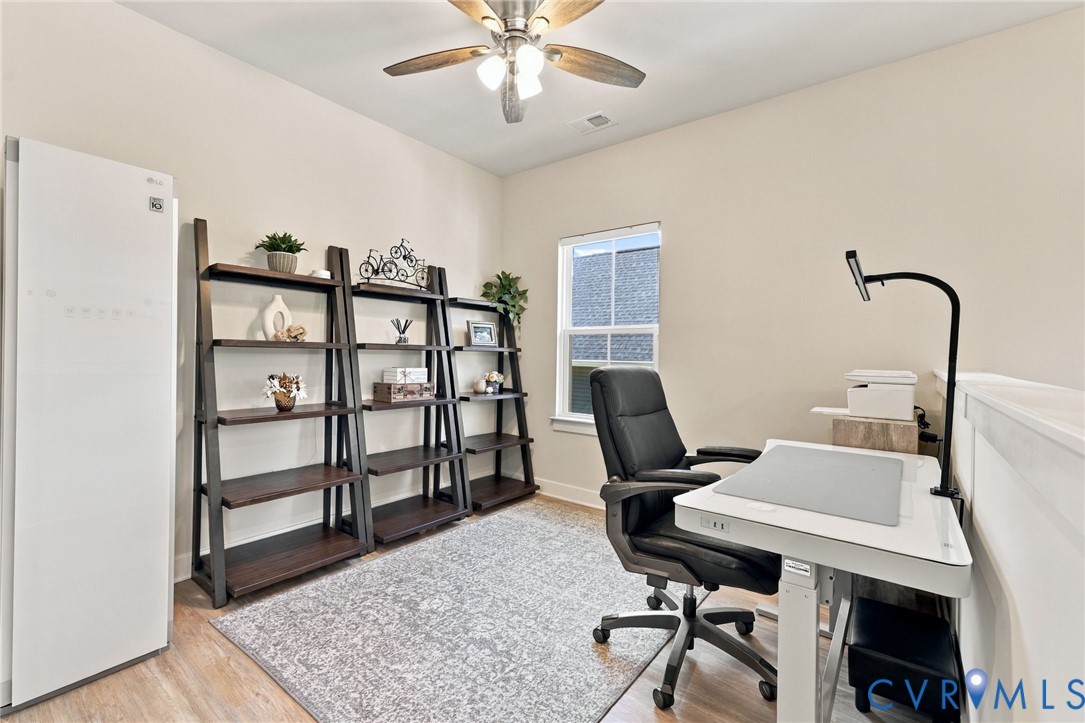 Multi-use interior space featuring wood-finish flooring, a single-hung window, and a ceiling fan with integrated lighting