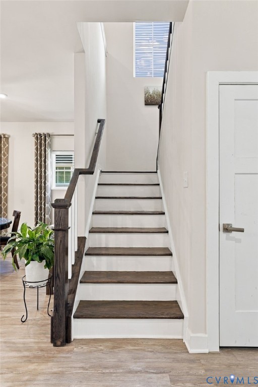 Staircase featuring dark-stained wood treads, white risers, a wood-finish handrail, and square balusters