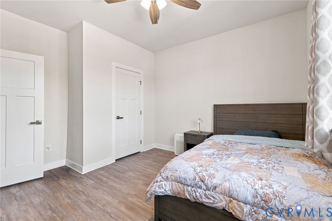 Neutral-toned interior featuring wood-finish flooring, two shaker-style panel doors, and a ceiling fan with integrated lighting
