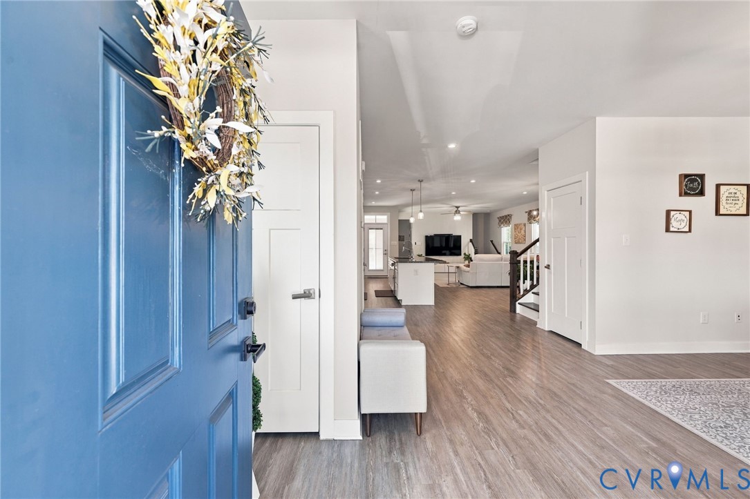 Blue entry door featuring a multi-panel design, wood-finish flooring, and recessed ceiling lighting Blue entry door featuring a multi-panel design, wood-finish flooring, and recessed ceiling lighting
