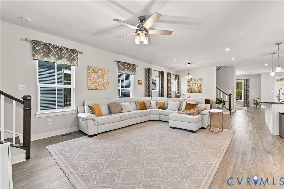 Open-concept interior featuring wood-finish flooring, recessed lighting, a modern ceiling fan, and large windows with natural light