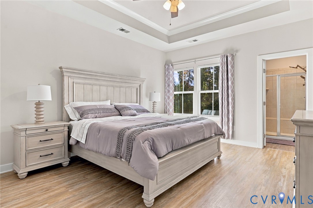 Tray ceiling with recessed lighting, wood-finish flooring, and dual-pane windows