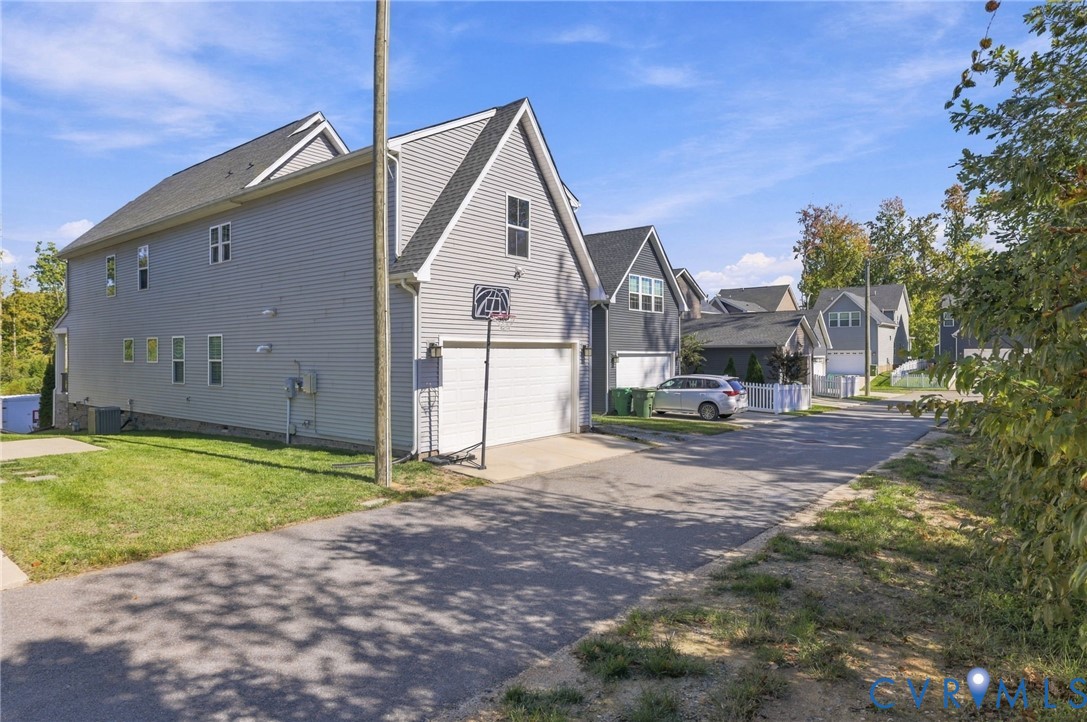 Two-story residence featuring light gray horizontal siding, a steeply pitched roofline, an attached two-car garage, and asphalt driveway