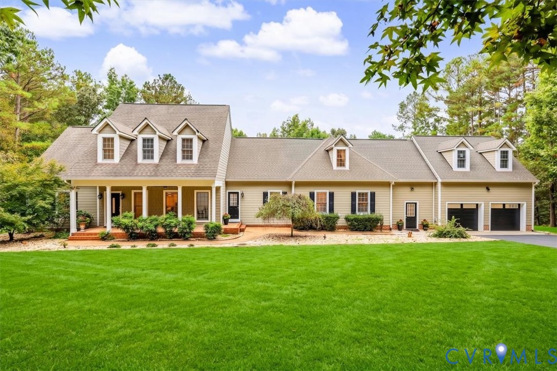 Traditional exterior featuring light-toned horizontal siding, a covered front porch, decorative dormer windows, and an attached two-car garage Traditional exterior featuring light-toned horizontal siding, a covered front porch, decorative dormer windows, and an attached two-car garage