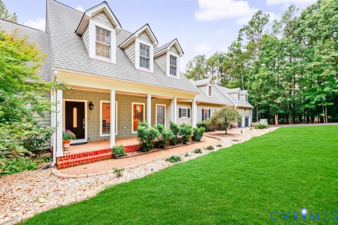 Exterior featuring a shingle-style facade, gabled dormers, an expansive covered porch with brick steps, and a manicured lawn
