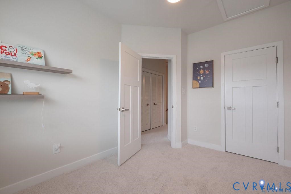 Neutral-toned interior featuring wall-mounted floating shelves, carpeted flooring, and shaker-style interior doors with satin nickel hardware