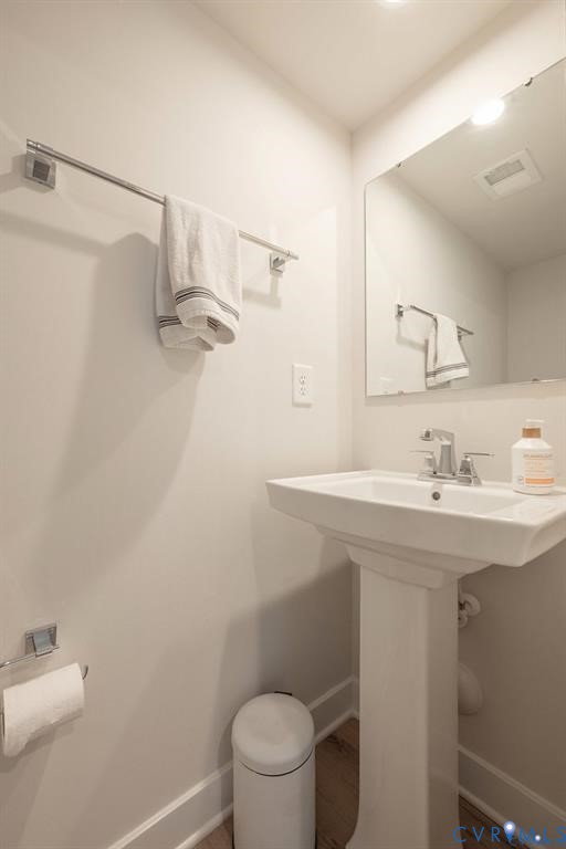 Pedestal sink with chrome faucet, large rectangular mirror, and chrome towel hardware