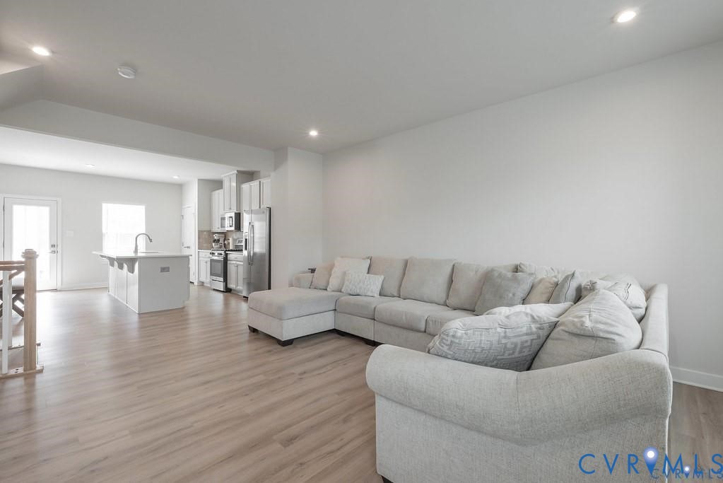 Open floor plan featuring wood-finish flooring, recessed lighting, and a kitchen island with a built-in sink