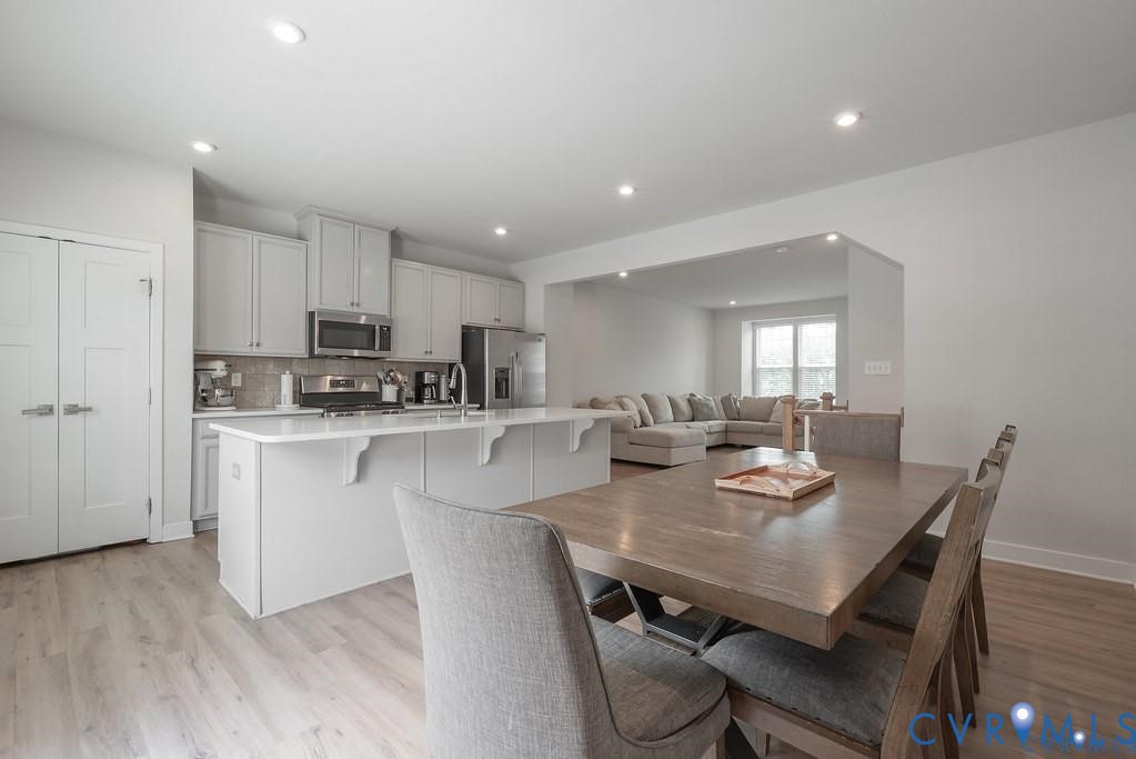 Kitchen featuring white cabinetry, an expansive island with a countertop, stainless steel appliances, and wood-finish flooring