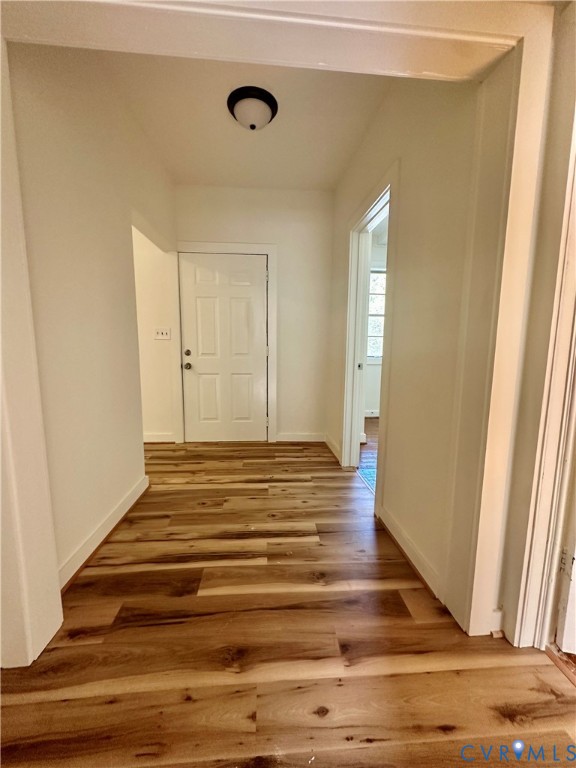 Entryway featuring wood-finish flooring, a six-panel exterior door, and a flush-mount ceiling light fixture