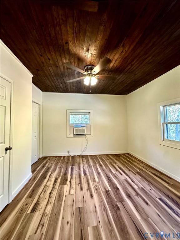 Interior room featuring a natural wood-plank ceiling, wood-finish flooring, two windows, and a built-in ceiling fan with light fixture