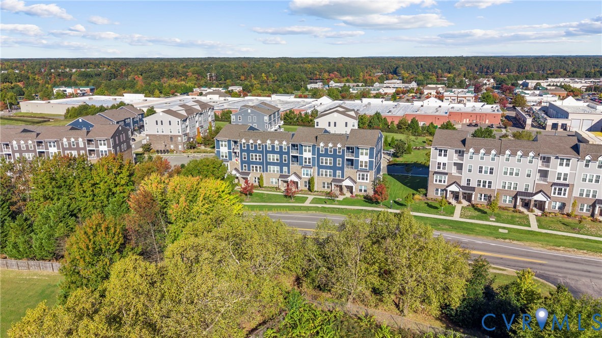 Aerial perspective of multi-story residential buildings featuring blue and grey siding, masonry lower-level facades, gabled rooflines, and private balconies
