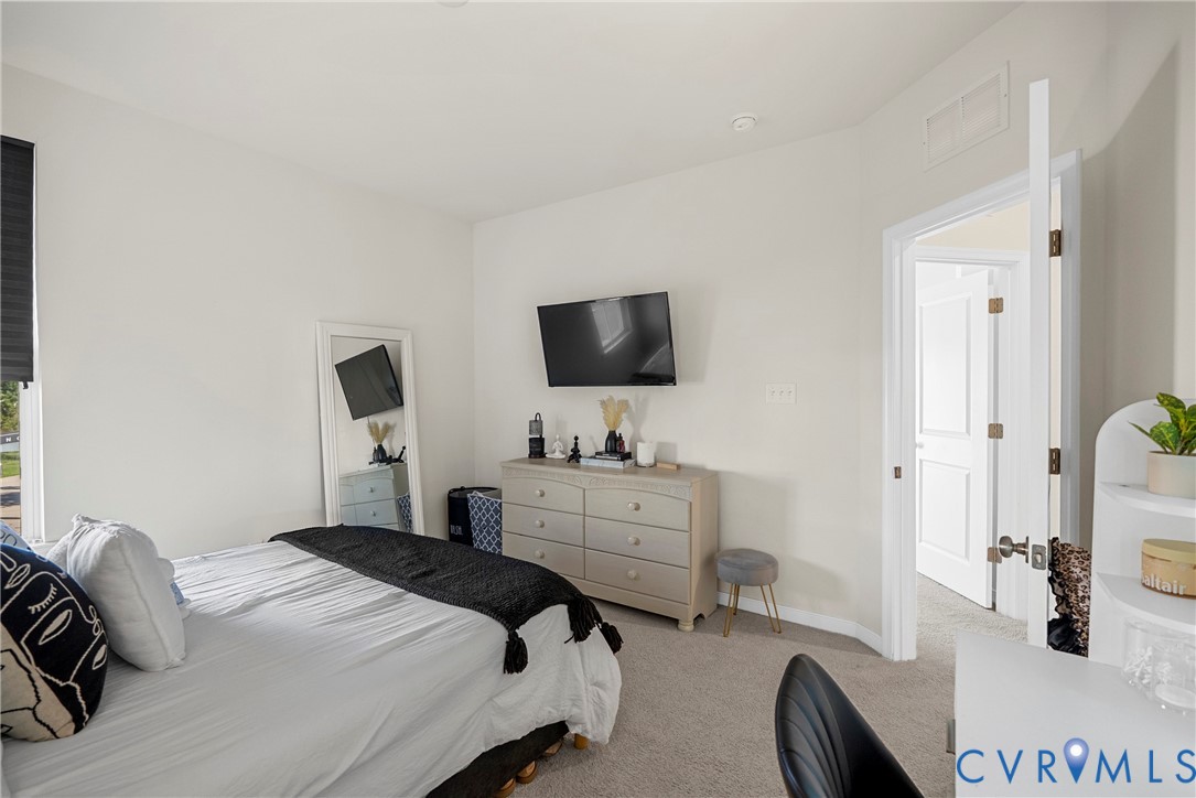 Neutral-toned room featuring plush wall-to-wall carpeting, crisp white walls, and a recessed paneled door
