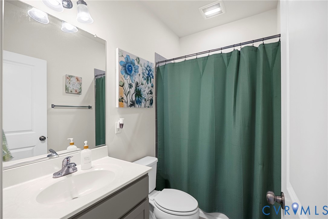 Bathroom featuring a vanity with an integrated basin, polished metal faucet, large wall-mounted mirror, overhead three-light fixture, and a combination tub and shower