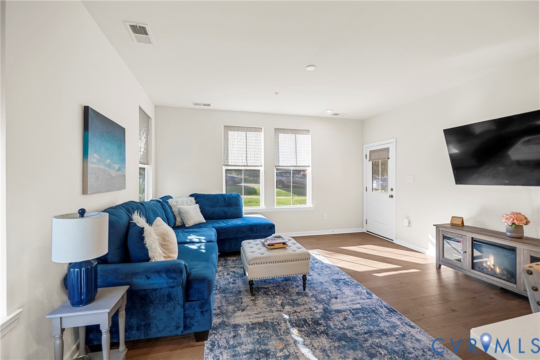 Living area featuring wood-finish flooring, recessed lighting, and dual windows with shades