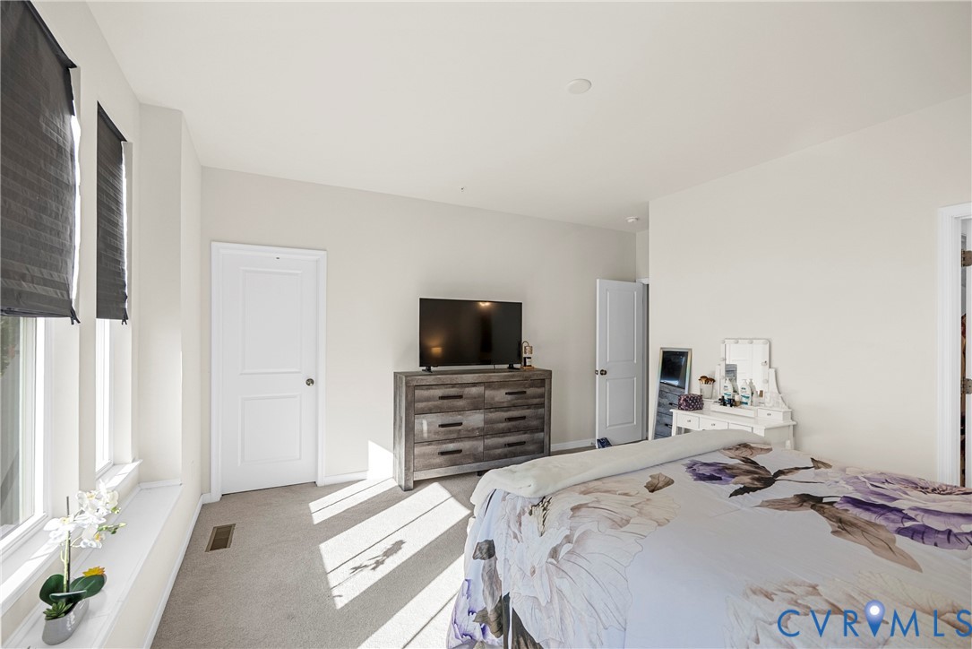 Neutral-toned bedroom featuring carpeted flooring, two paneled doors, and large windows with integrated shades
