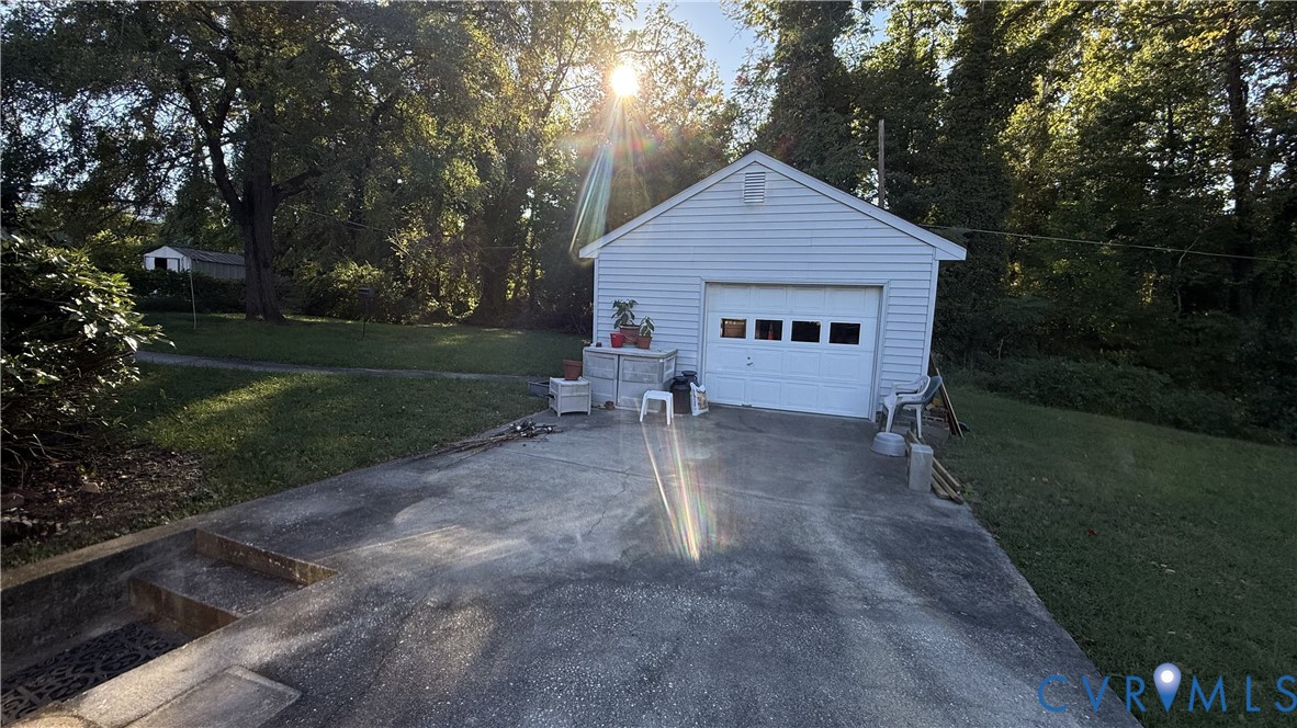 Detached garage with horizontal siding, multi-pane window garage door, concrete driveway, and expansive lawn Detached garage with horizontal siding, multi-pane window garage door, concrete driveway, and expansive lawn