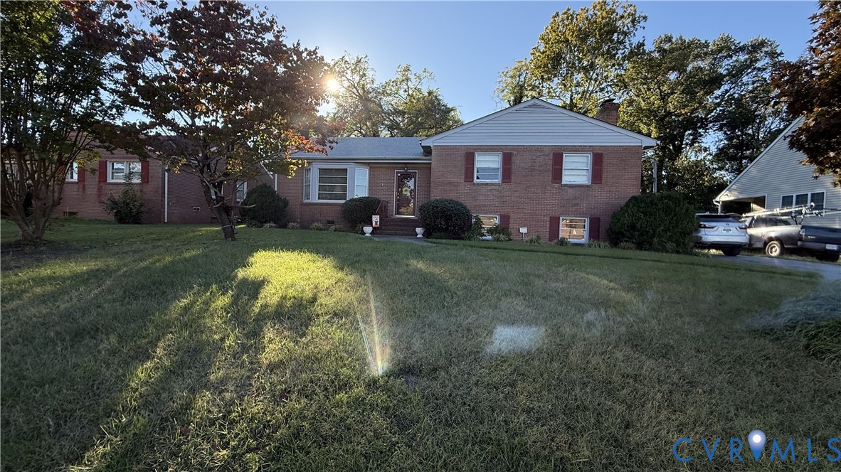 Brick exterior residence featuring a front bay window, decorative shutters, and expansive lawn area