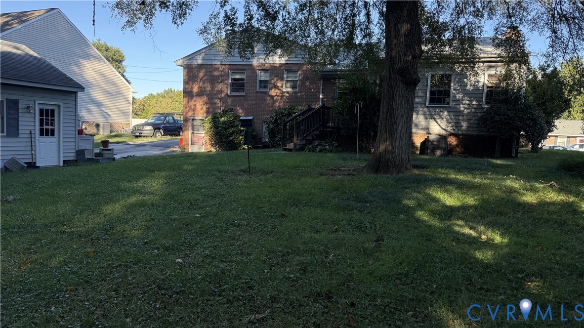 Brick and vinyl exterior featuring a spacious lawn, mature trees, and wooden staircase Brick and vinyl exterior featuring a spacious lawn, mature trees, and wooden staircase