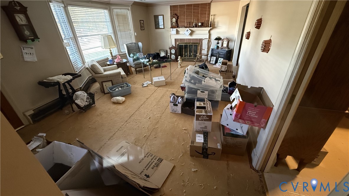 Living area featuring a bay window, masonry fireplace with a mantel, and carpeted flooring Living area featuring a bay window, masonry fireplace with a mantel, and carpeted flooring