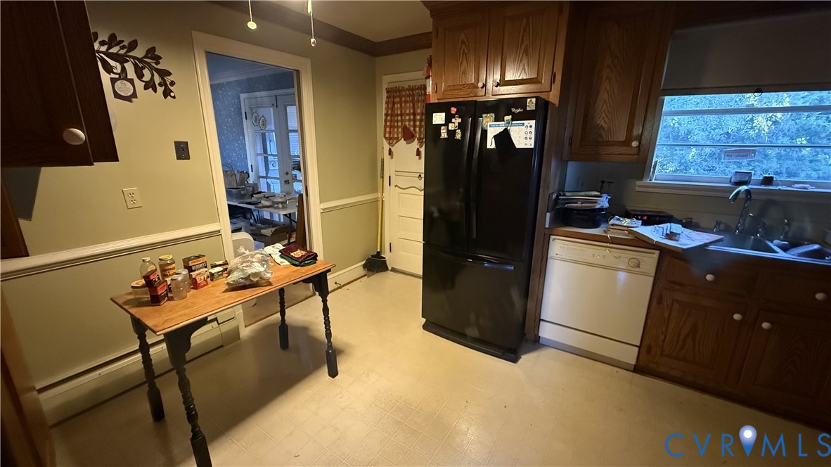 Kitchen featuring wood cabinetry, chair rail molding, and a dual-basin sink with a gooseneck faucet Kitchen featuring wood cabinetry, chair rail molding, and a dual-basin sink with a gooseneck faucet