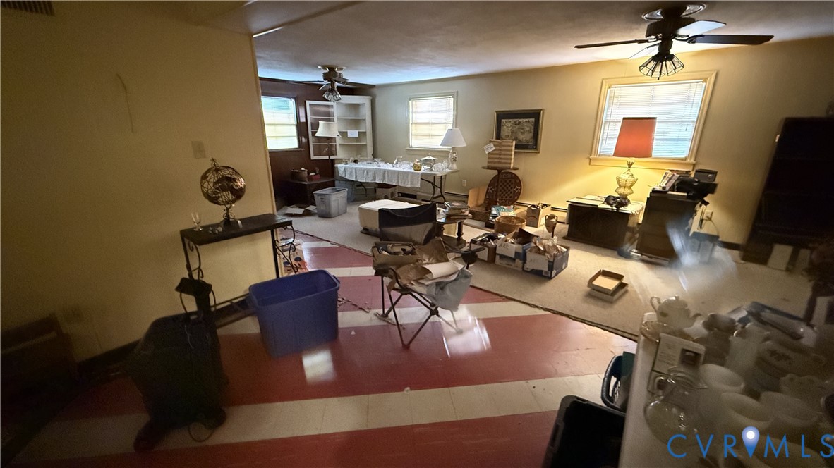 Interior space featuring two ceiling-mounted light fixtures with integrated fans, red and white striped flooring, wall-to-wall carpeting, and built-in shelving Interior space featuring two ceiling-mounted light fixtures with integrated fans, red and white striped flooring, wall-to-wall carpeting, and built-in shelving