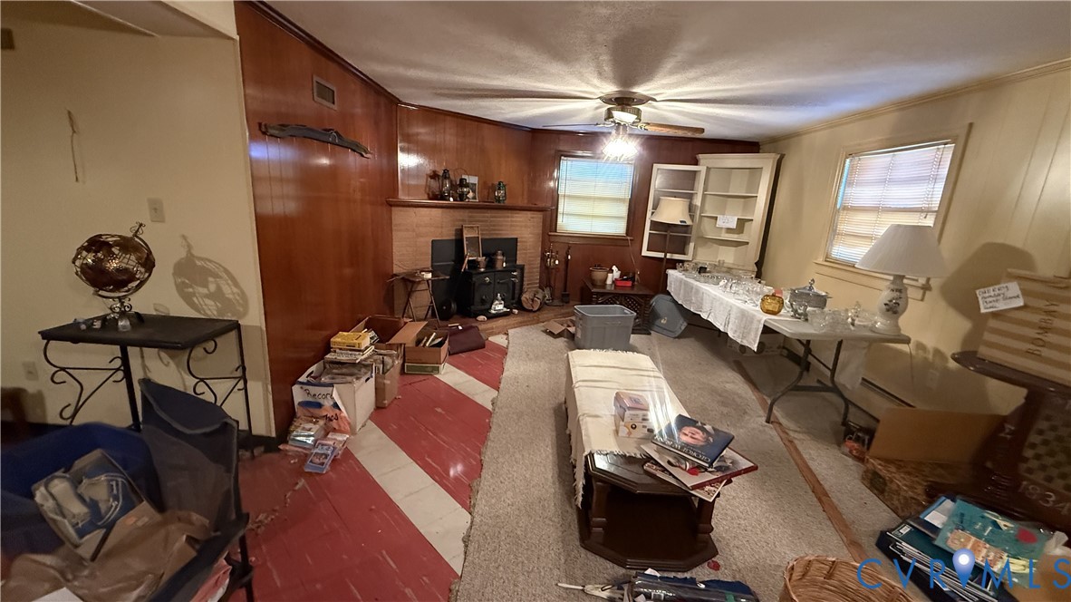 Wood-panelled accent wall, stone-surround fireplace, built-in shelving unit, and ceiling fan Wood-panelled accent wall, stone-surround fireplace, built-in shelving unit, and ceiling fan