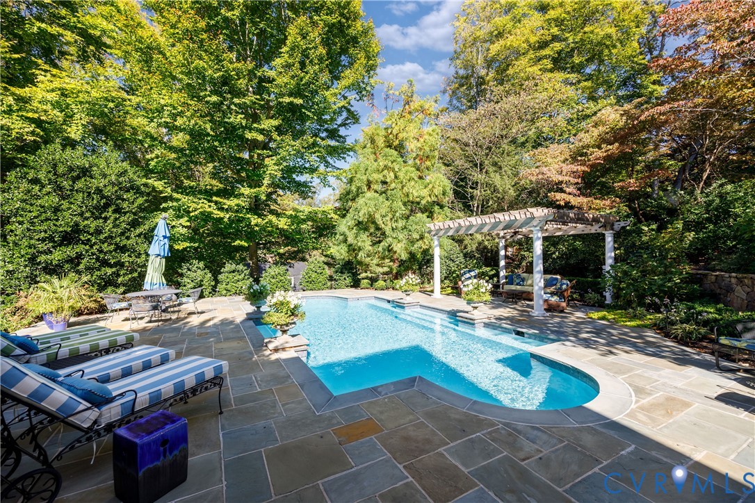In-ground saltwater, heated pool with flagstone decking and a custom pergola, surrounded by established trees and landscaping