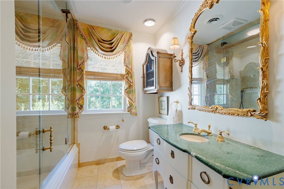 The hall bath features a cabinet/vanity with oval undermount sink, brass-tone hardware, a glass-enclosed shower with a soaking tub, and tile flooring.