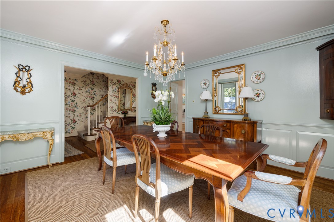 Dining room features wainscoting, crown moulding, hardwood floor and a crystal chandelier