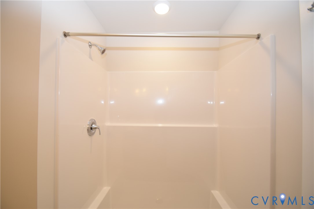 Bathtub and shower combination featuring a seamless acrylic surround, single-handle faucet, integrated showerhead, and a metal shower curtain rod