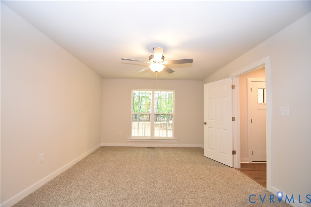 Interior room featuring neutral wall paint, carpeted flooring, a ceiling fan with integrated lighting, and a multi-pane window