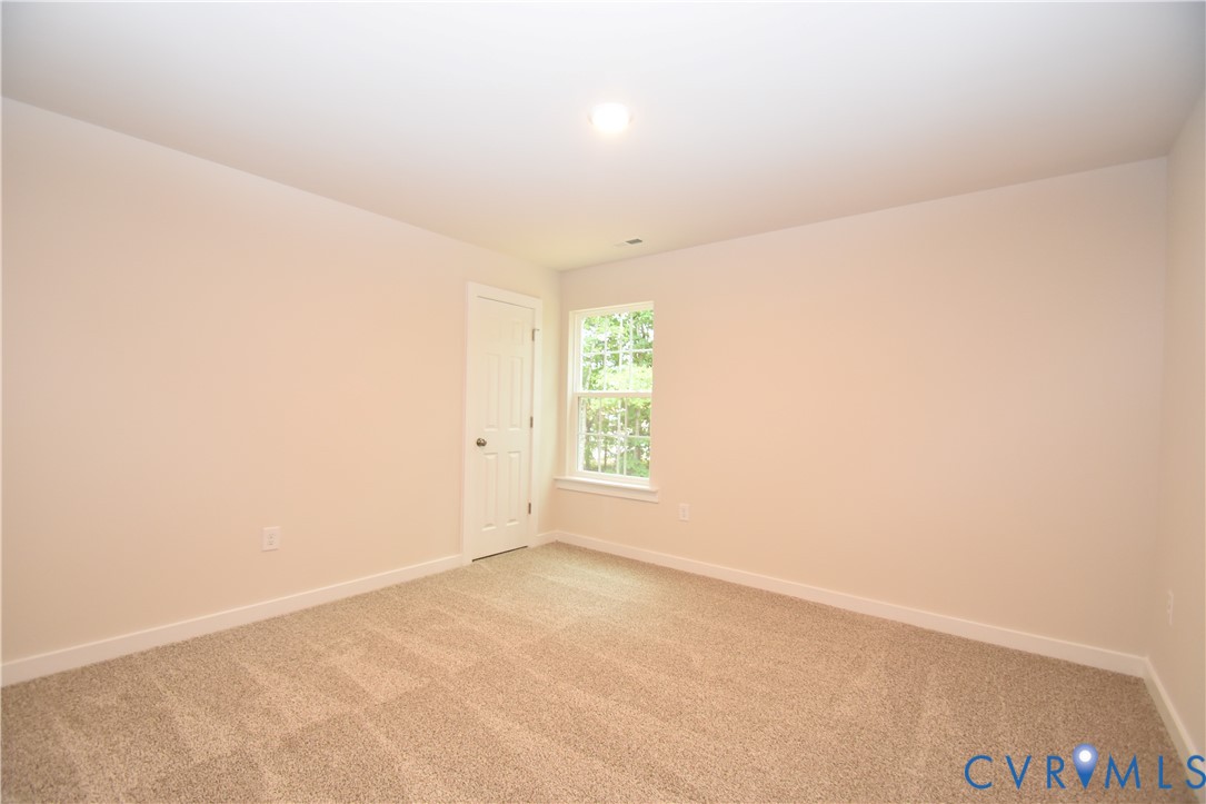 Neutral wall-to-wall carpeting, single-panel interior door, and double-hung window with natural exterior exposure