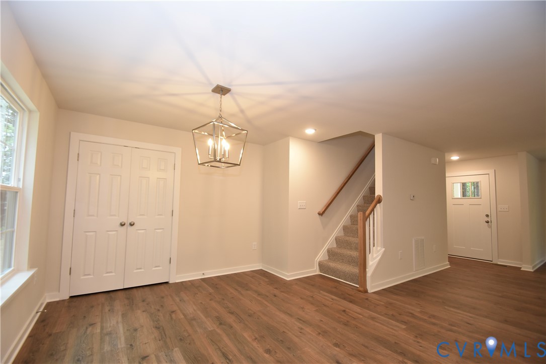Wood-finish flooring, geometric metal pendant lighting, double-panel doors, and staircase with a wood handrail