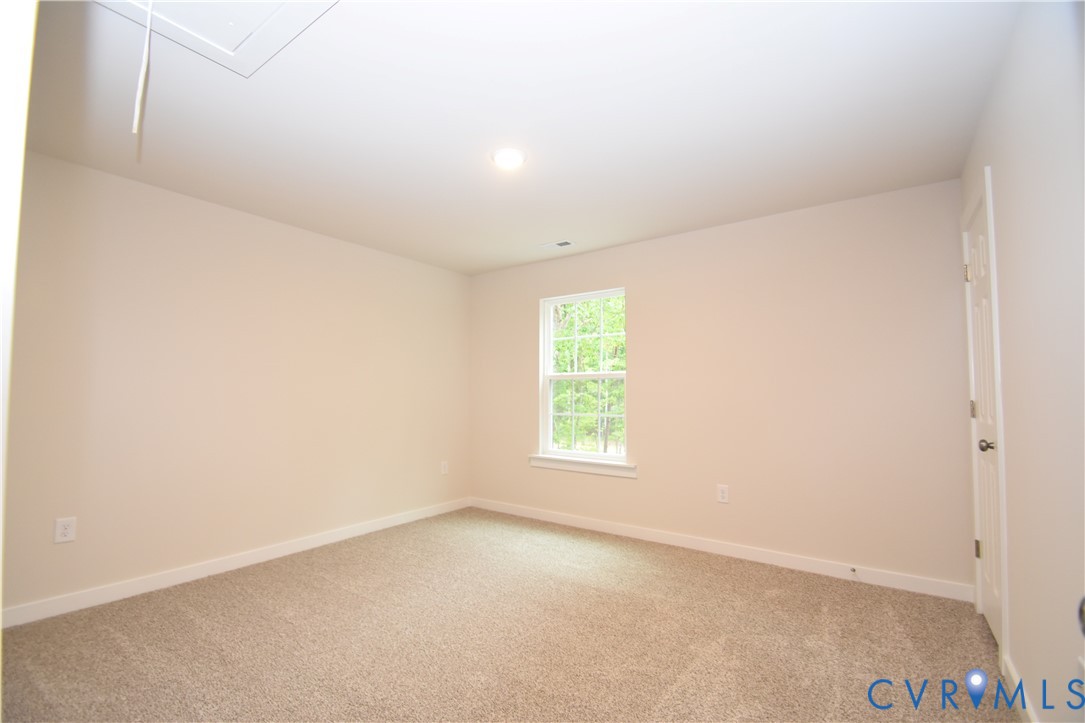 Neutral-toned interior space featuring wall-to-wall carpeting, a single-pane window with white trim, and a six-panel door