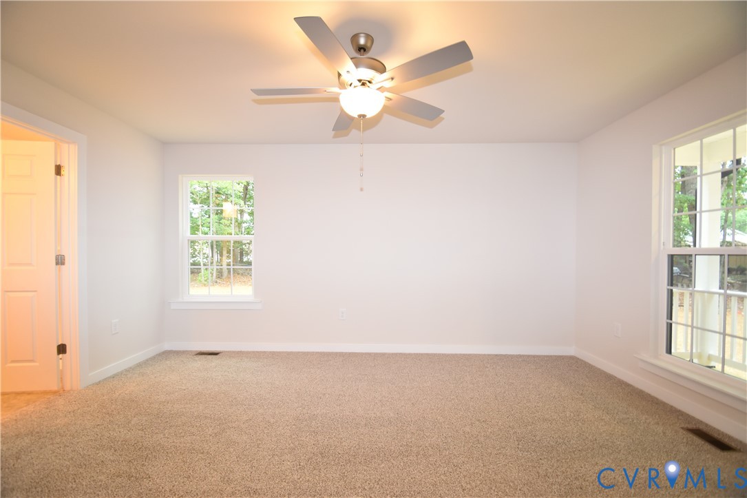 Neutral-toned carpeting, multi-pane windows, and a central ceiling fan with integrated lighting