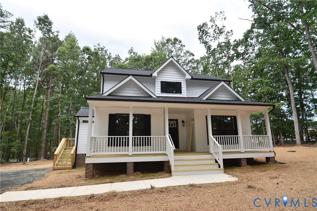 Exterior facade featuring white horizontal siding, dark shutters, a covered front porch with white railing, and a gabled roofline Exterior facade featuring white horizontal siding, dark shutters, a covered front porch with white railing, and a gabled roofline