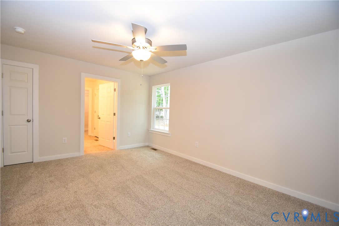 Neutral-toned room featuring neutral carpeting, a ceiling fan with integrated lighting, two six-panel doors, and a single-pane window