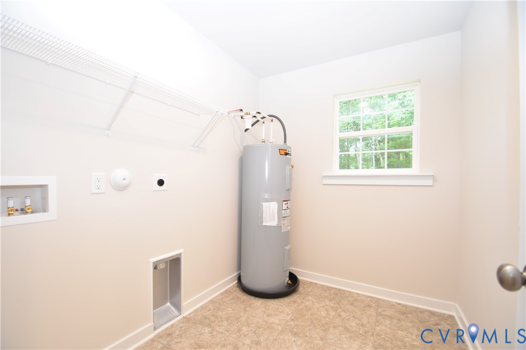 Utility space featuring wall-mounted wire shelving, a window with a sill, resilient tile-patterned flooring, and plumbing connections