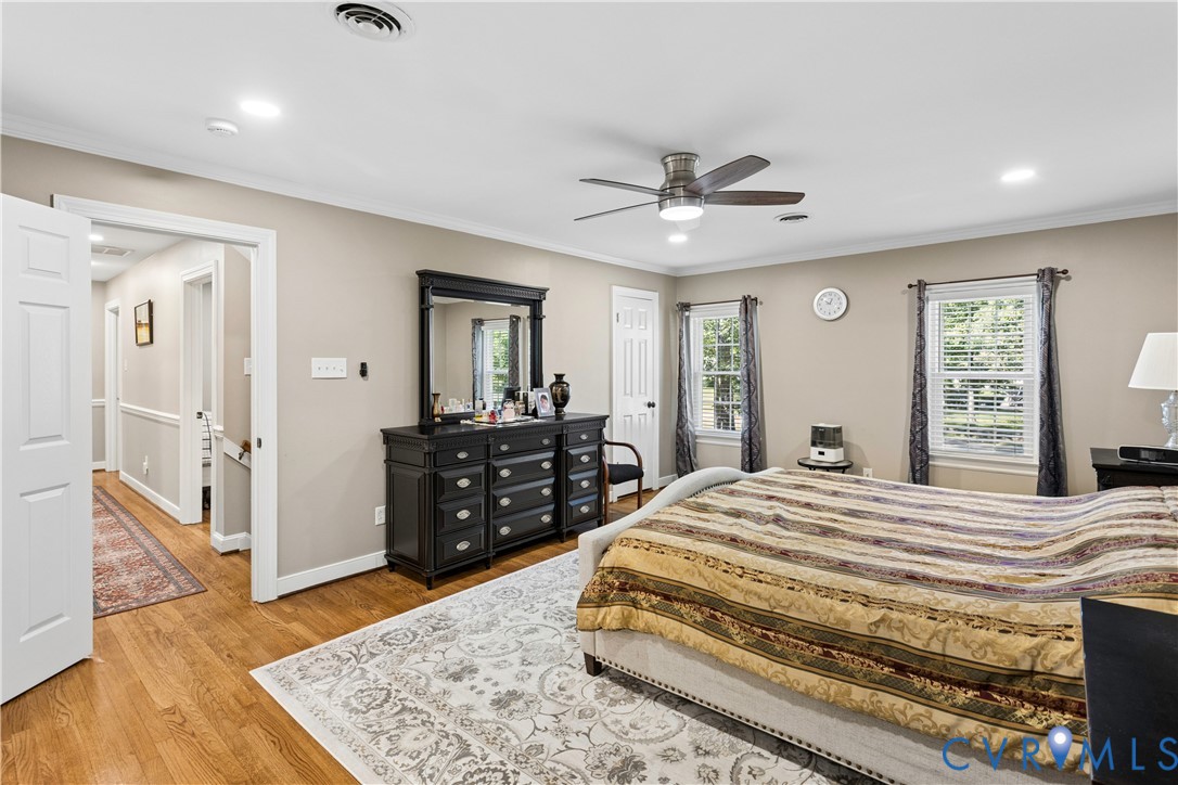 Room featuring wood-finish flooring, recessed lighting, a ceiling fan with integrated light fixture, and two windows with casing trim