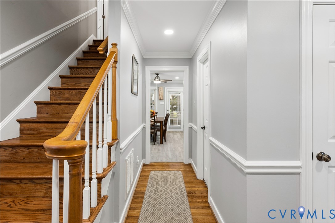 Staircase featuring wood-finish treads, white balusters, and a wooden handrail, complemented by crown molding, chair rail trim, and recessed lighting